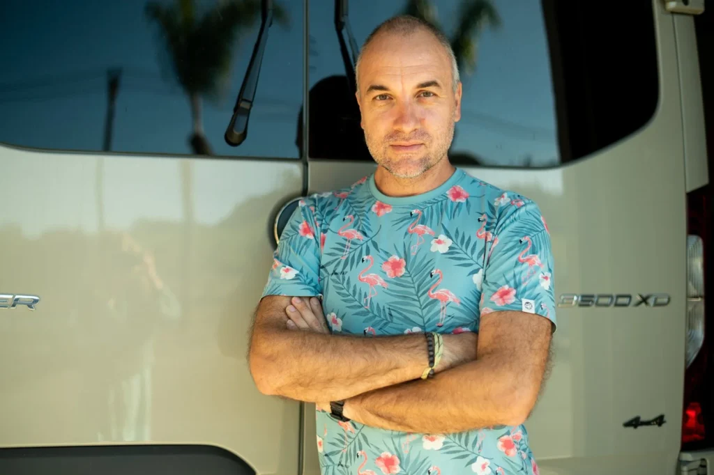 Michael, founder of Exmotech, standing with arms crossed in front of a van.